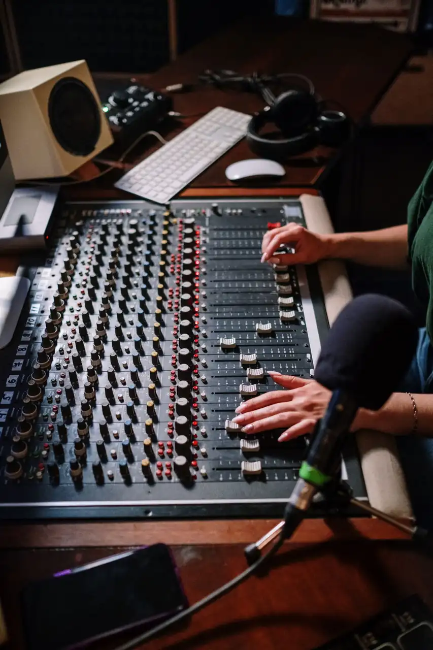 Audio engineer adjusting levels on a mixing console for music recording
